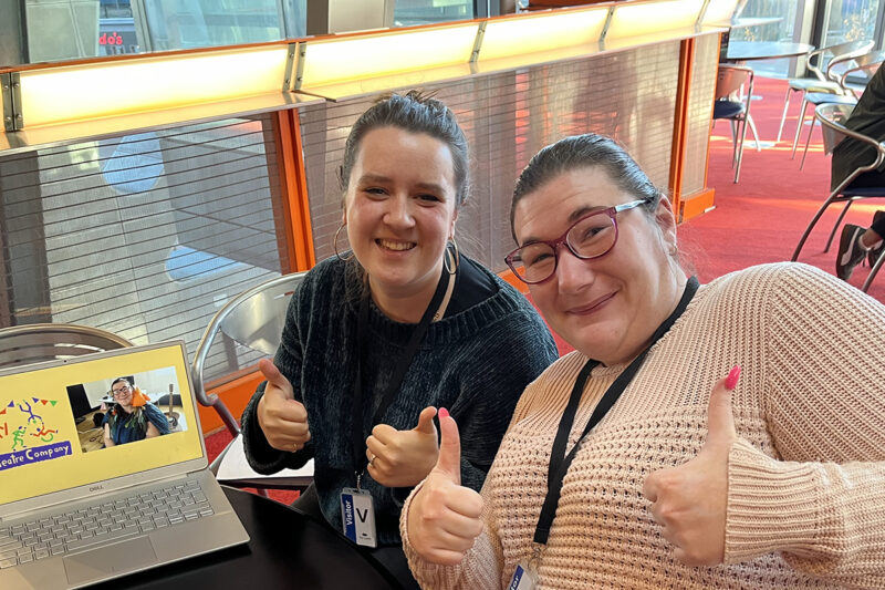 photo; close up of two women. They are both doing thumbs up and smiling at the camera. On the table next to them is a laptop and we can see on the screen the DIY logo and a photo of one of the women.