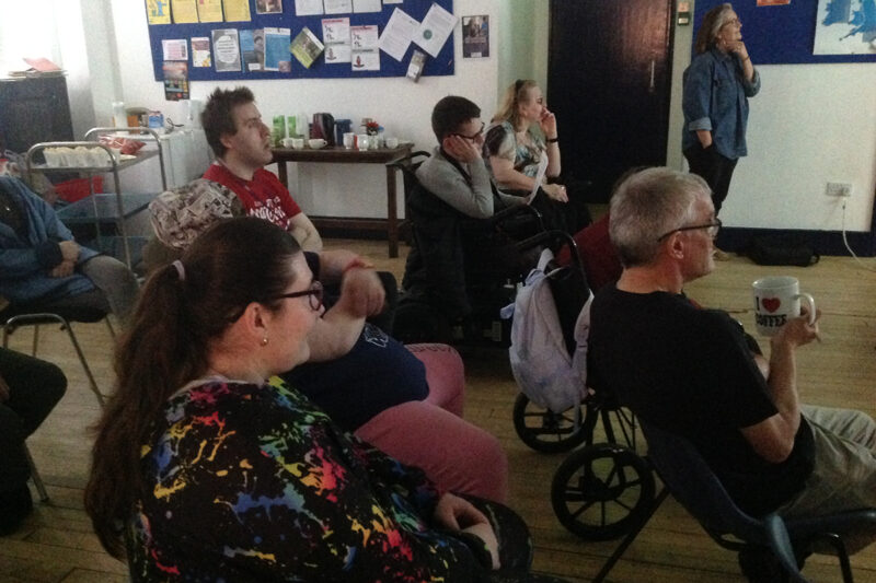 photo: people are sitting in a darkened room all looking the same way and concentrating.